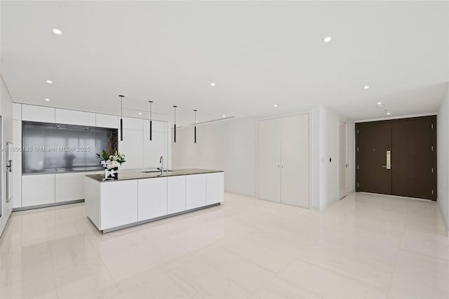 kitchen with a kitchen island with sink, recessed lighting, a sink, white cabinetry, and modern cabinets