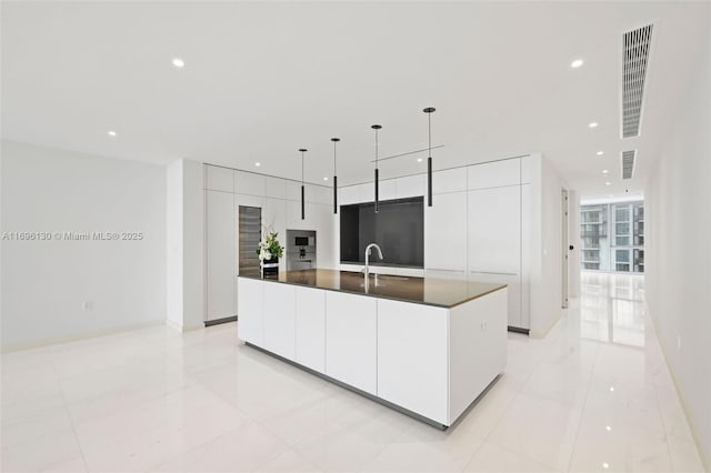 kitchen featuring light tile patterned floors, white cabinetry, a spacious island, dark countertops, and modern cabinets