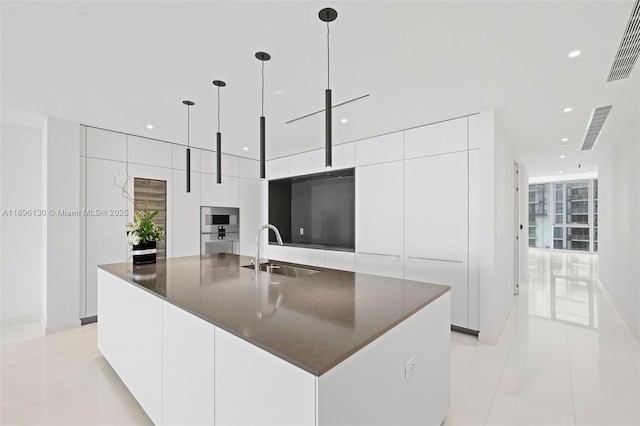 kitchen featuring a sink, visible vents, white cabinets, modern cabinets, and a large island with sink