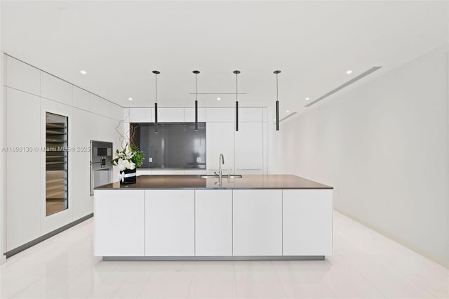 kitchen with dark countertops, modern cabinets, a sink, and white cabinetry