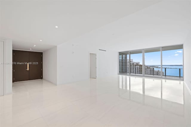 empty room featuring a water view, light tile patterned flooring, and floor to ceiling windows