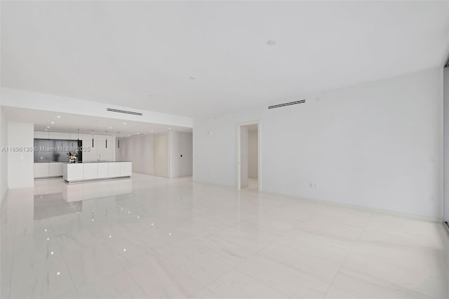 unfurnished living room with recessed lighting and marble finish floor