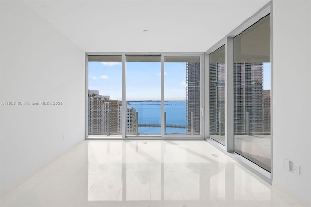 empty room featuring a water view and tile patterned flooring