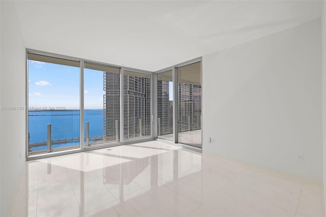 tiled empty room with a water view and expansive windows