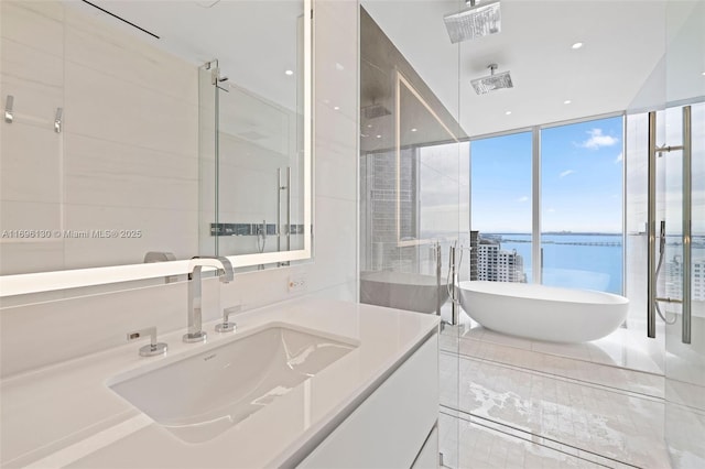 full bathroom featuring visible vents, a water view, a freestanding bath, a stall shower, and vanity