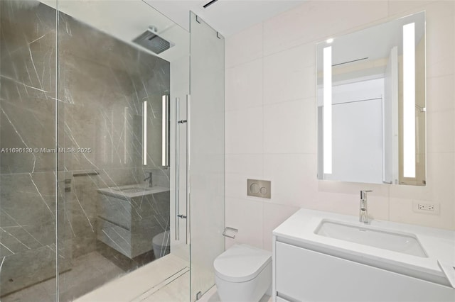 bathroom with a marble finish shower, tile walls, toilet, and vanity