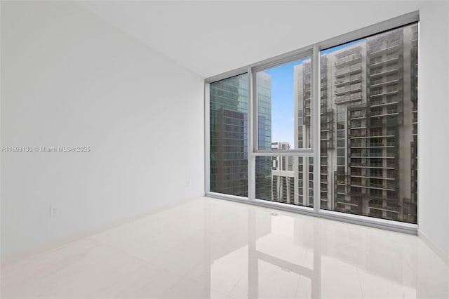 spare room with a view of city, tile patterned floors, and expansive windows