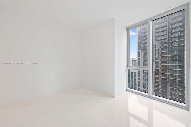 unfurnished room featuring baseboards and a wall of windows