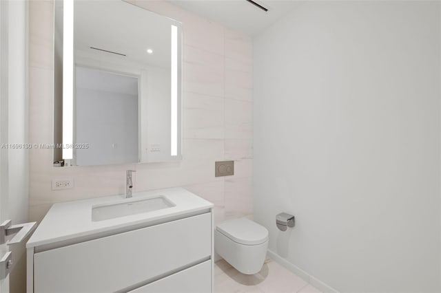 half bath featuring toilet, tile patterned floors, tile walls, and vanity