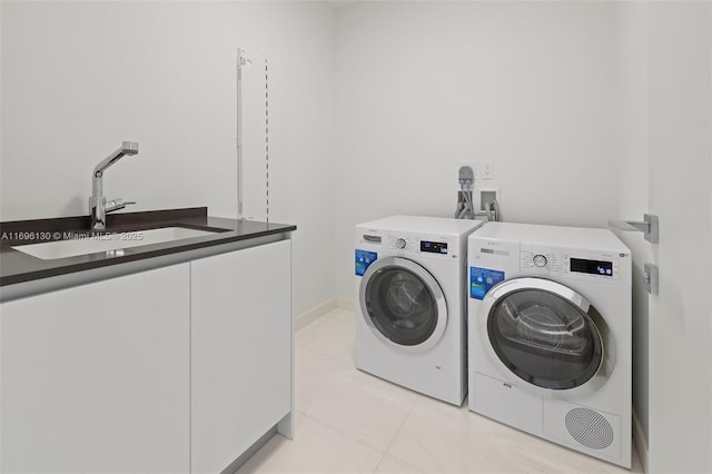 laundry room featuring light tile patterned floors, washer and dryer, cabinet space, and a sink