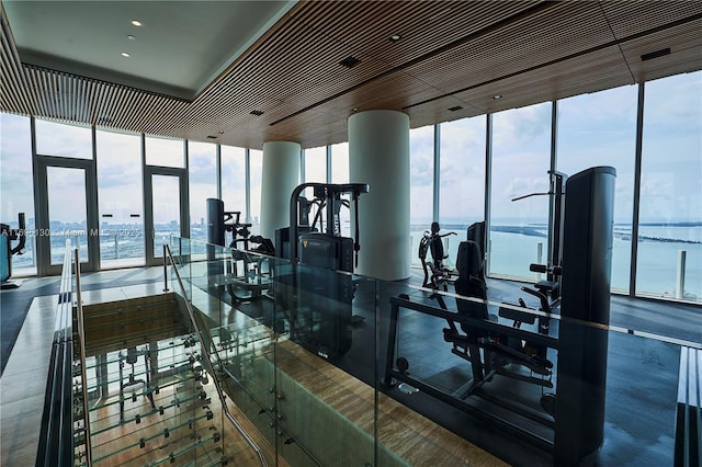 exercise room featuring french doors, expansive windows, and a water view