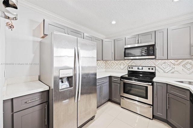 kitchen with gray cabinetry, ornamental molding, and appliances with stainless steel finishes