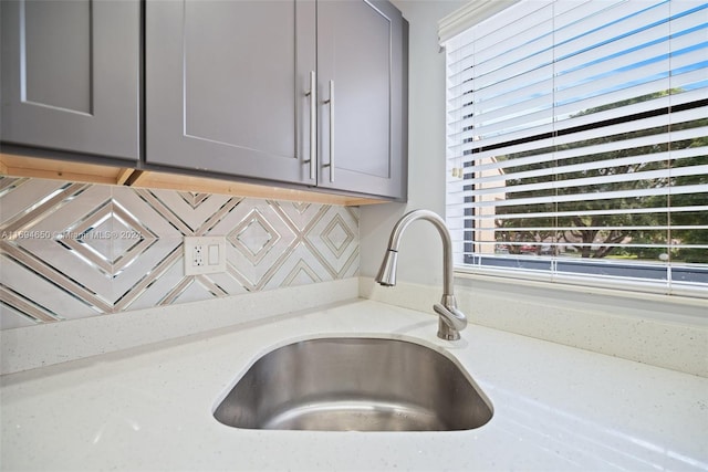 kitchen featuring gray cabinets, light stone counters, a healthy amount of sunlight, and sink