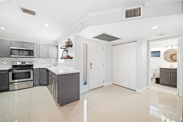 kitchen featuring gray cabinetry, decorative backsplash, light tile patterned floors, and appliances with stainless steel finishes