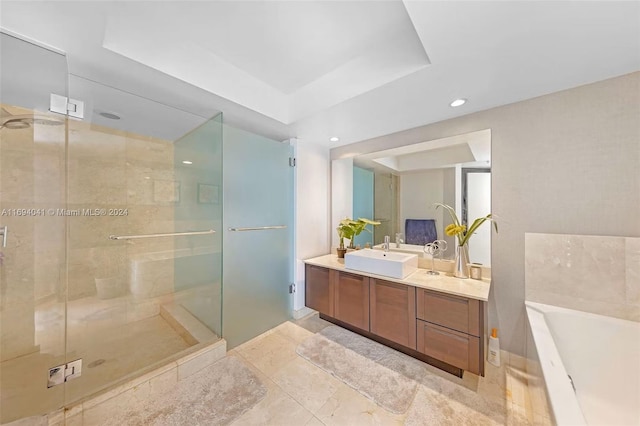 bathroom with a tray ceiling, vanity, and plus walk in shower