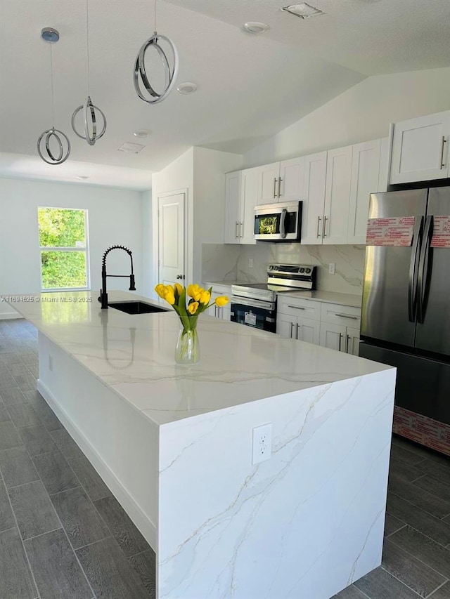 8036 104th Ct, Vero Beach, FL 32967 - kitchen featuring appliances with stainless steel finishes, a sink, backsplash, white cabinetry, and vaulted ceiling