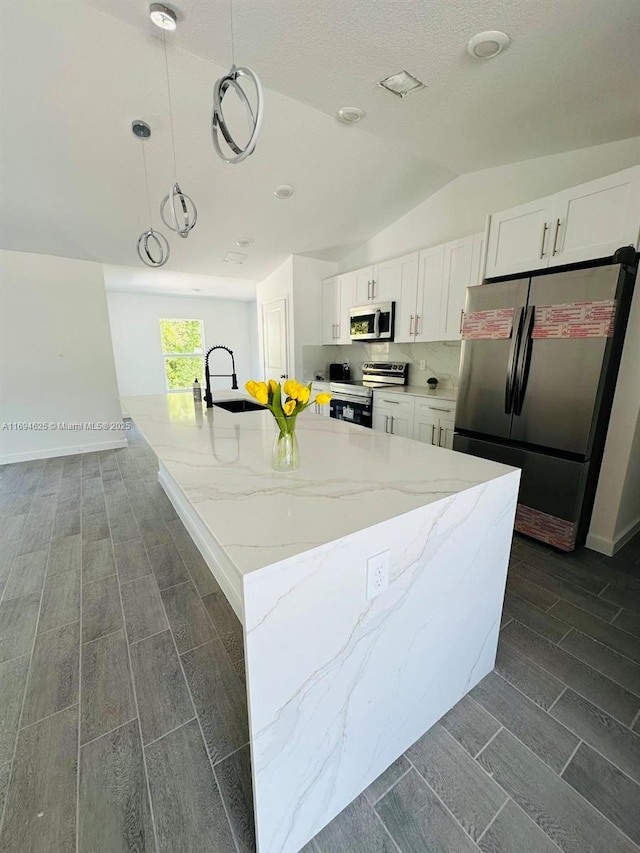 8036 104th Ct, Vero Beach, FL 32967 - kitchen featuring appliances with stainless steel finishes, a sink, white cabinetry, light stone countertops, and vaulted ceiling