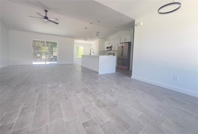 8036 104th Ct, Vero Beach, FL 32967 - unfurnished living room featuring vaulted ceiling, a sink, ceiling fan, baseboards, and light wood-type flooring