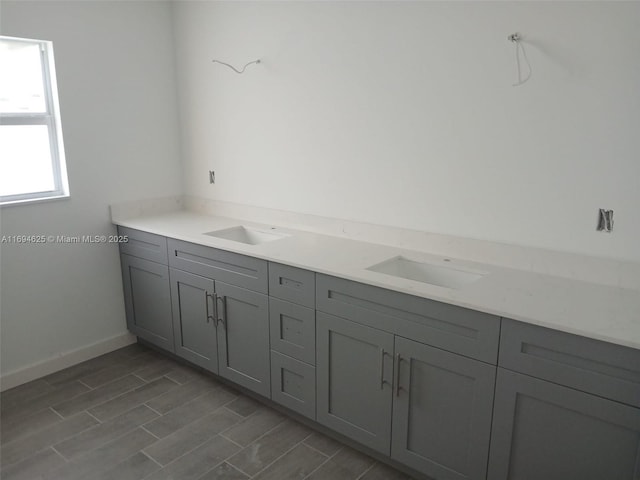 interior space with double vanity, wood finish floors, a sink, and baseboards