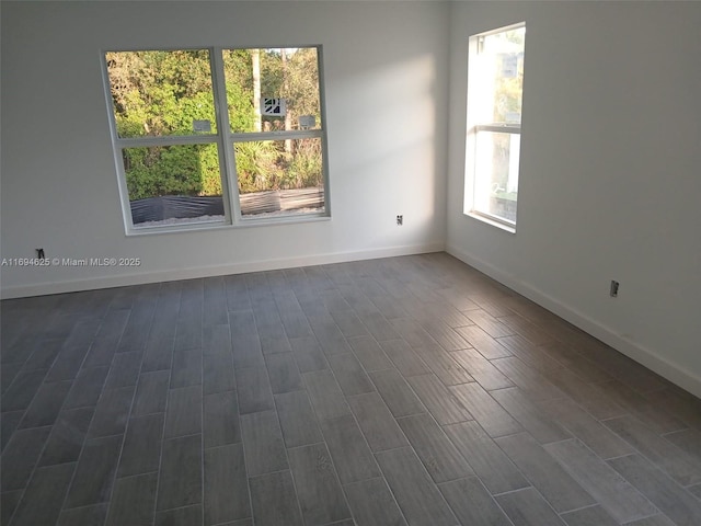 spare room with baseboards, dark wood finished floors, and a healthy amount of sunlight