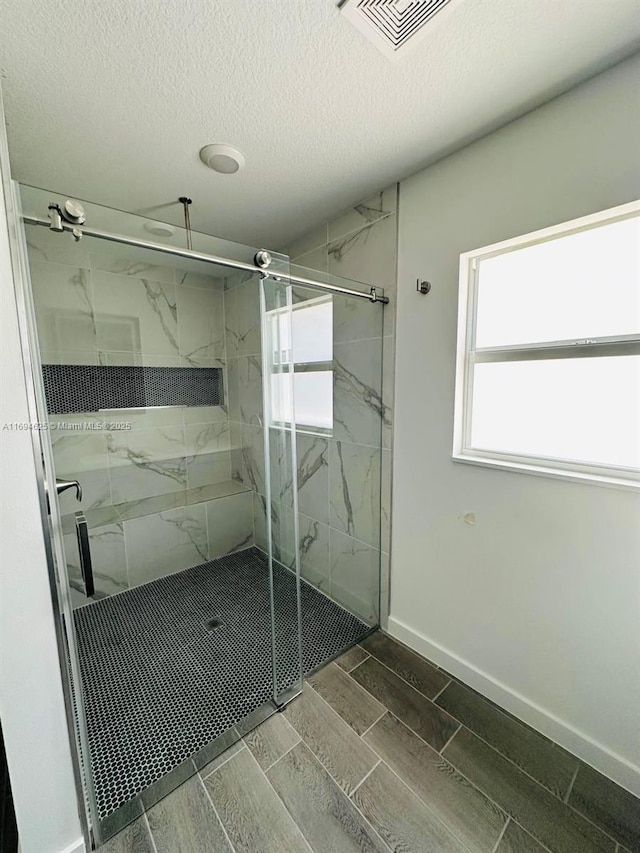 8036 104th Ct, Vero Beach, FL 32967 - full bathroom with wood tiled floors, a marble finish shower, a textured ceiling, and baseboards