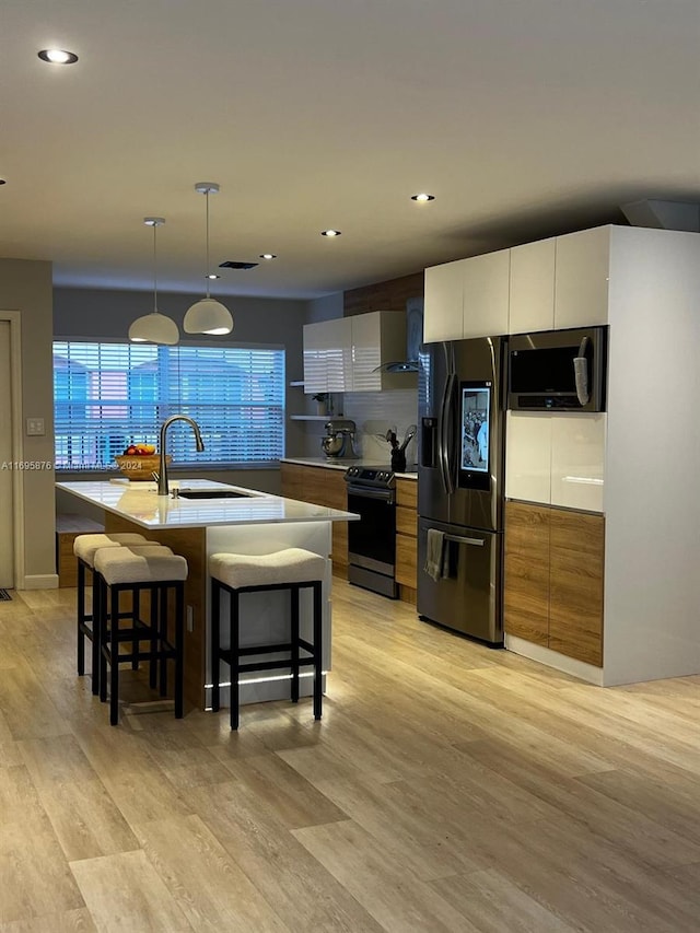 kitchen with white cabinets, sink, an island with sink, and appliances with stainless steel finishes