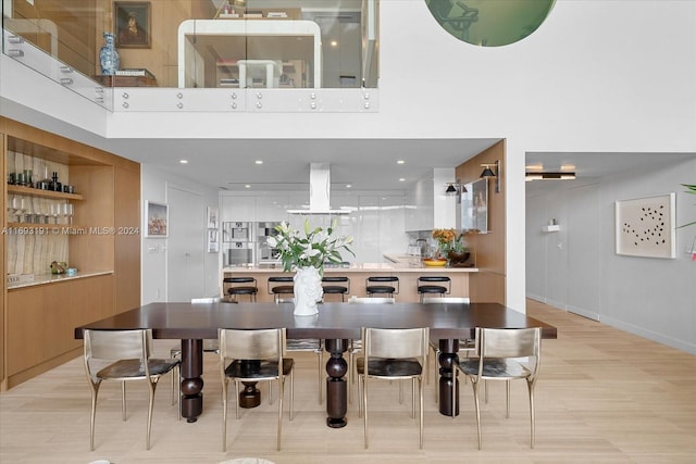 dining area with a high ceiling and light hardwood / wood-style floors