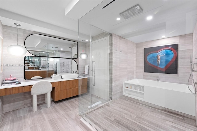 bathroom featuring vanity, plus walk in shower, and tile walls