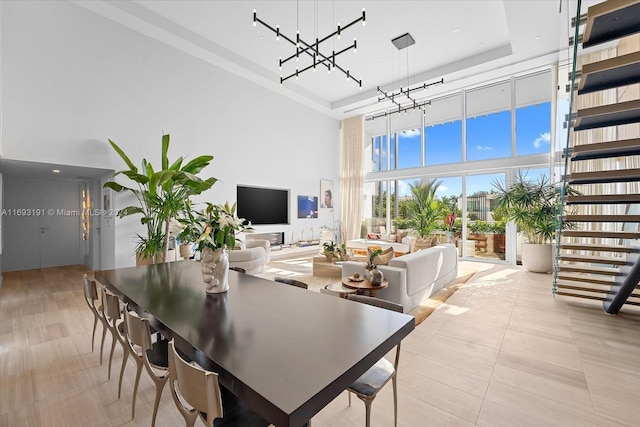 dining space featuring a tray ceiling, floor to ceiling windows, light tile patterned floors, and a high ceiling