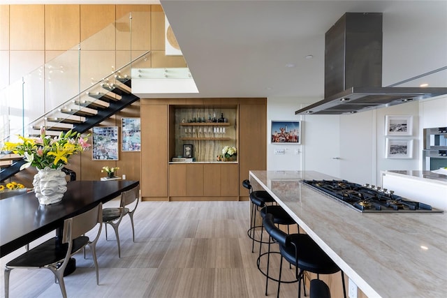 kitchen featuring a breakfast bar, wall chimney range hood, and appliances with stainless steel finishes