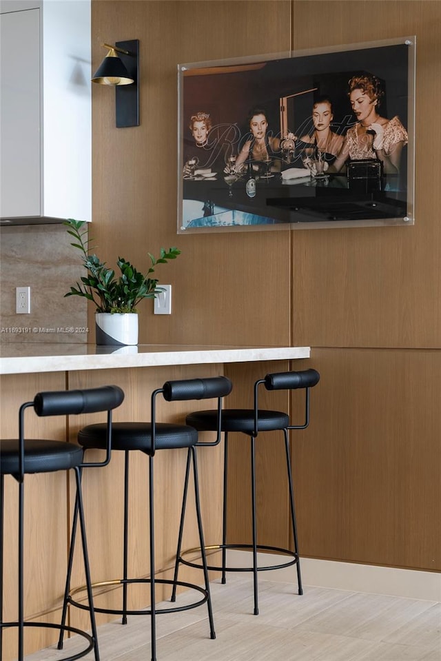 bar featuring light wood-type flooring and tasteful backsplash