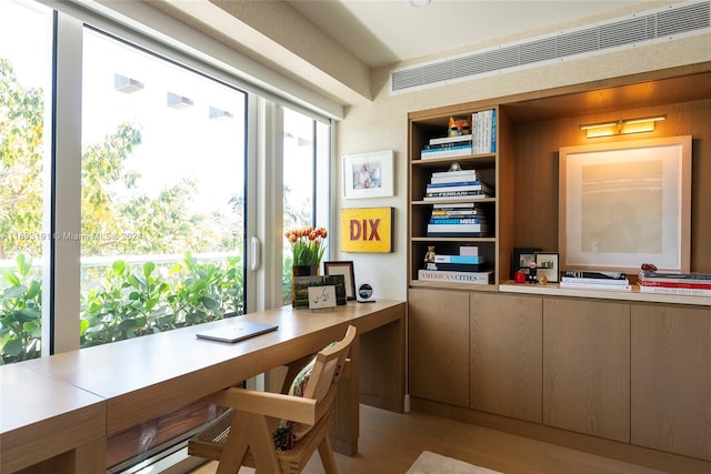 office with built in desk and light hardwood / wood-style flooring