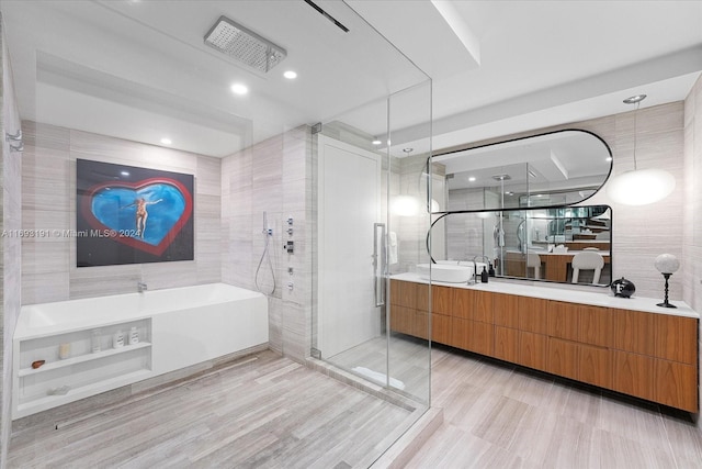 bathroom with vanity, separate shower and tub, and tile walls