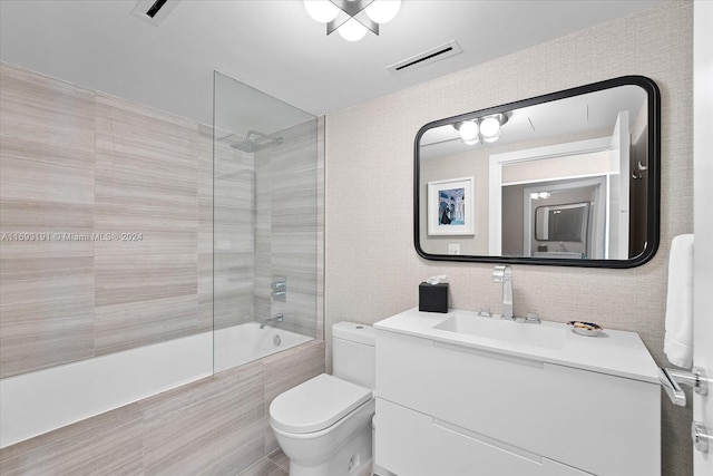 full bathroom featuring vanity, tiled shower / bath combo, and toilet