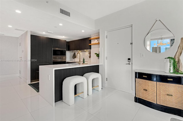 kitchen with a breakfast bar, sink, dark brown cabinetry, kitchen peninsula, and stainless steel appliances