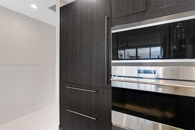 kitchen with stainless steel oven, light tile patterned floors, and built in microwave