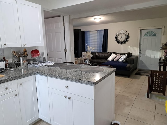 kitchen with white cabinetry, dark stone counters, light tile patterned flooring, and kitchen peninsula