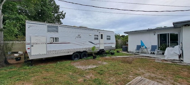 rear view of property featuring a yard and central AC unit