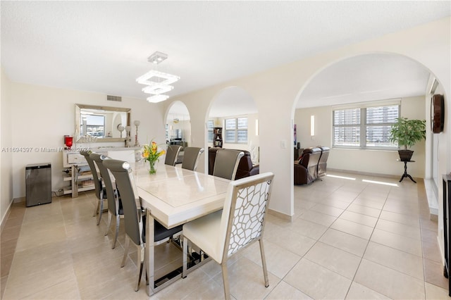 dining space with a wealth of natural light, light tile patterned floors, and a notable chandelier