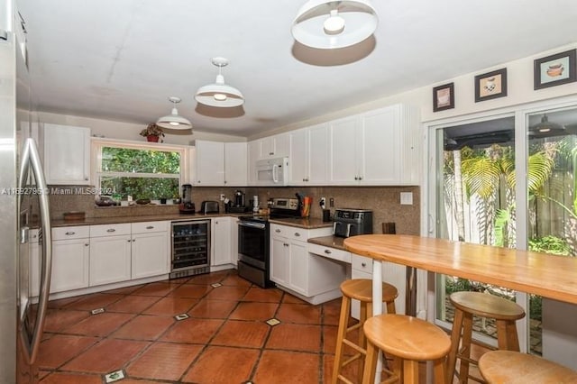 kitchen with stainless steel appliances, wine cooler, plenty of natural light, and white cabinetry