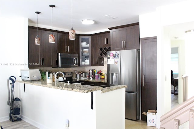 kitchen with kitchen peninsula, appliances with stainless steel finishes, decorative backsplash, light stone counters, and dark brown cabinetry