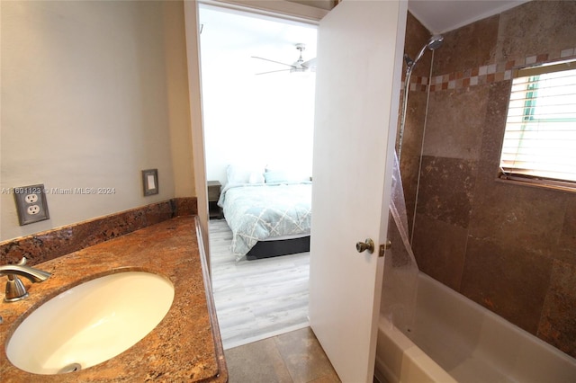 bathroom featuring tiled shower / bath, vanity, hardwood / wood-style flooring, and ceiling fan