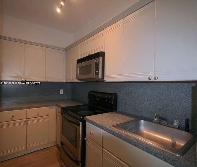 kitchen with appliances with stainless steel finishes, sink, backsplash, and wood-type flooring