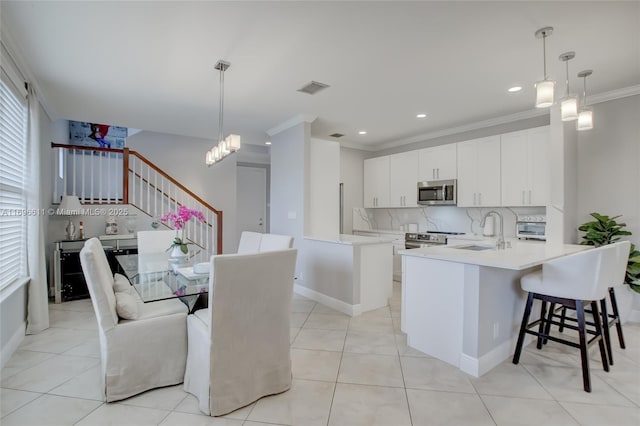 kitchen featuring pendant lighting, an island with sink, white cabinetry, sink, and stainless steel appliances