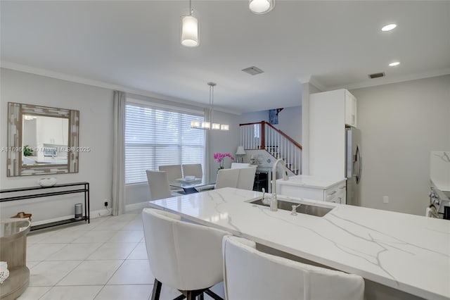 tiled dining space featuring sink, ornamental molding, and a chandelier