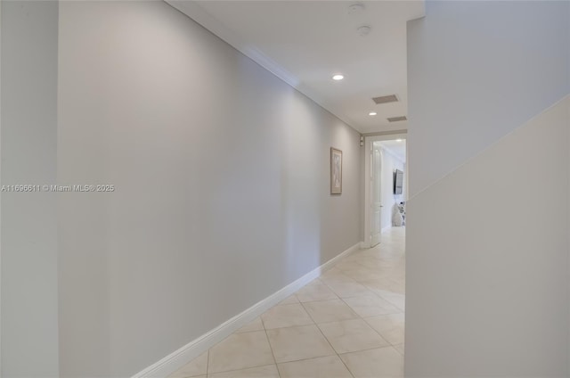 hall with ornamental molding and light tile patterned floors