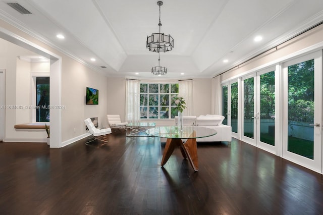 living room with a raised ceiling, dark hardwood / wood-style flooring, ornamental molding, and a chandelier