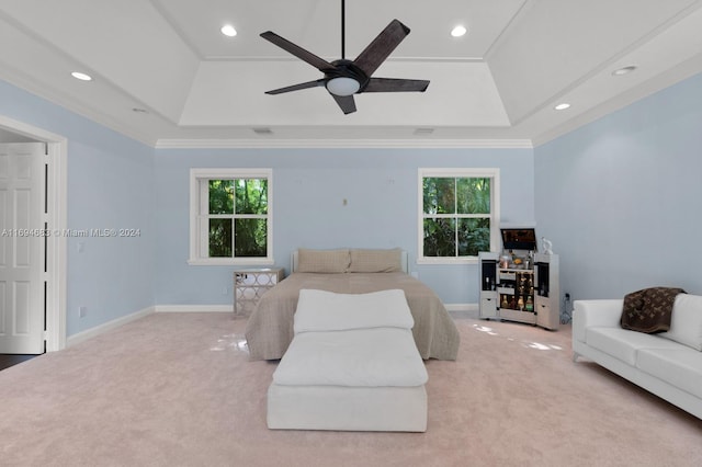 carpeted bedroom featuring a raised ceiling, multiple windows, ceiling fan, and crown molding