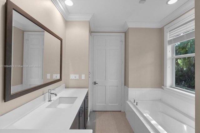 bathroom with plenty of natural light, ornamental molding, vanity, and tiled bath