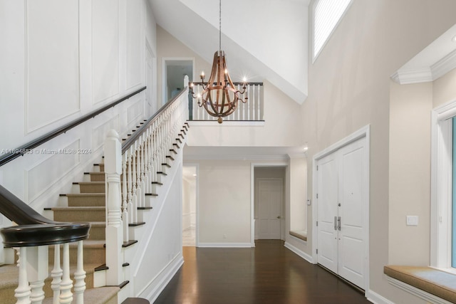 foyer entrance with a towering ceiling, dark hardwood / wood-style floors, and a notable chandelier